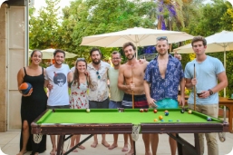 Friends pose at a party behind a pool table